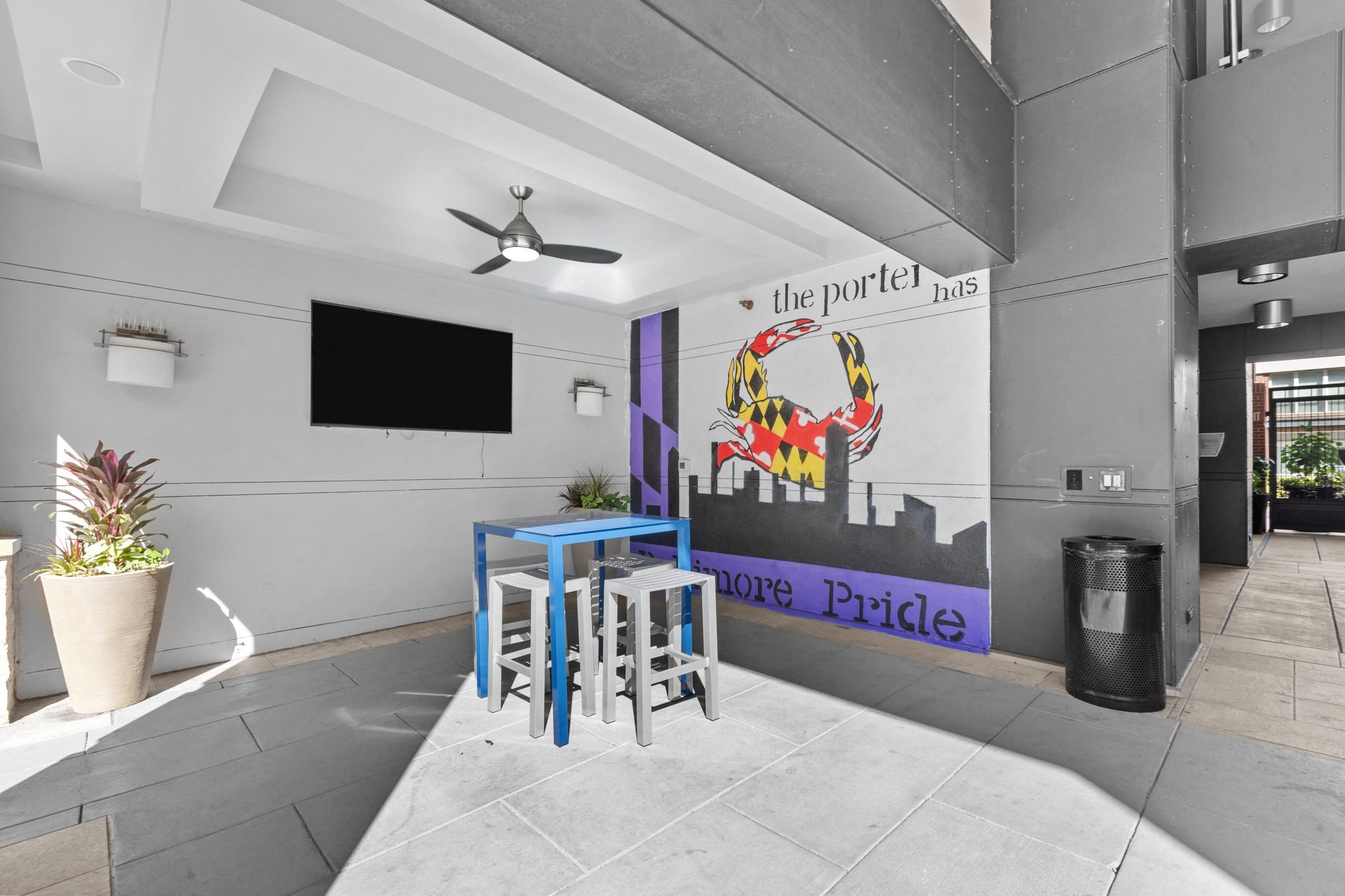 a room with a table and stools in front of a wall with a mural